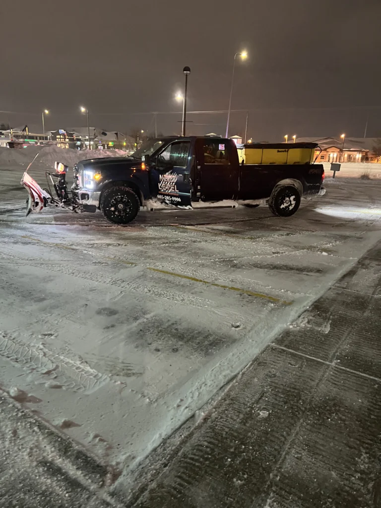 Snow removal truck with plow attachment parked in snowy lot, featuring "Next Level" branding, ready for HOA snow management services in Sioux Falls, SD.