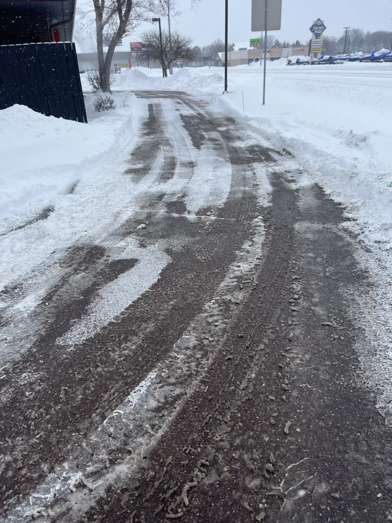 Snow-covered walkway with cleared tire tracks, showcasing snow removal services in Sioux Falls, SD.