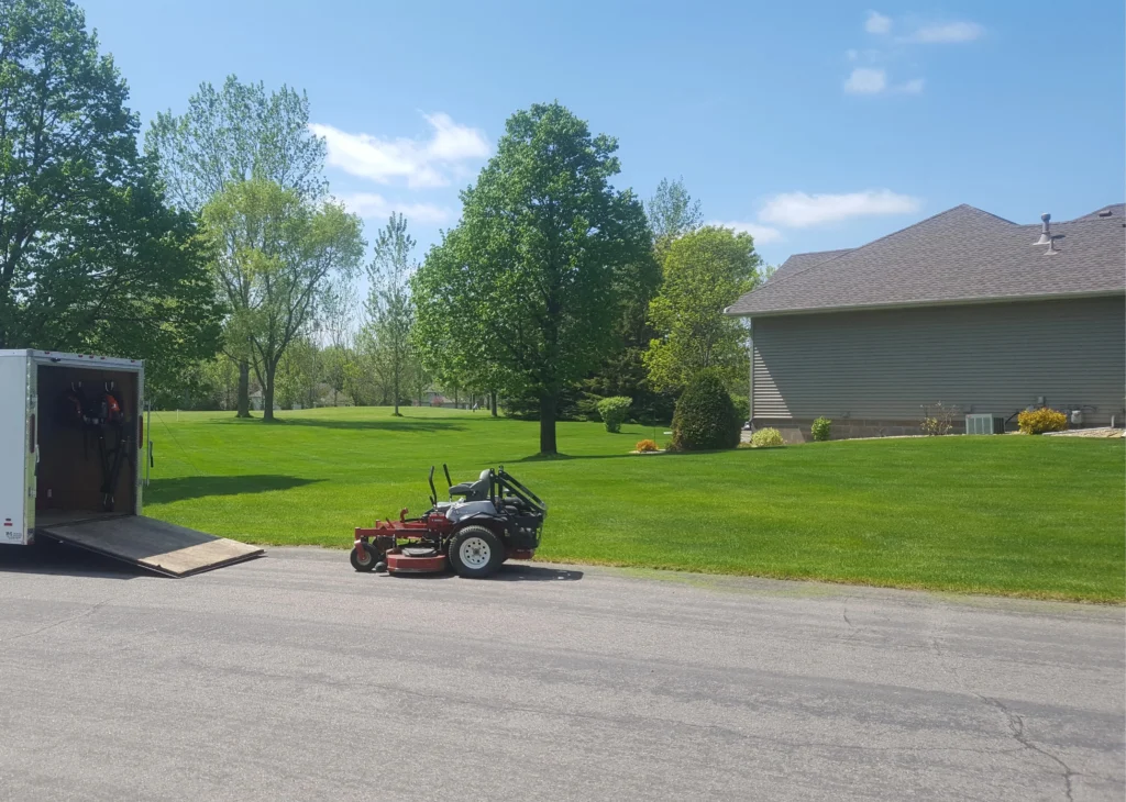 Lawn care equipment parked near a residential property with well-maintained grass, showcasing professional landscaping services by Next Level Outdoor Services in Sioux Falls, SD.